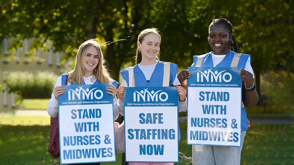 Two female nurses in scrubs standing outside the Oncology Unit smiling 